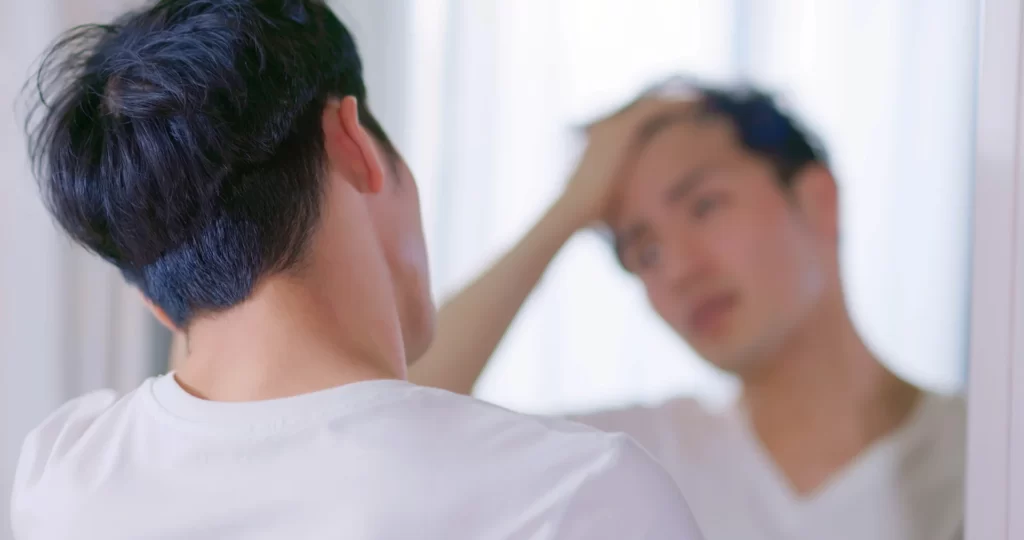 a man checking his hair loss in front of the mirror